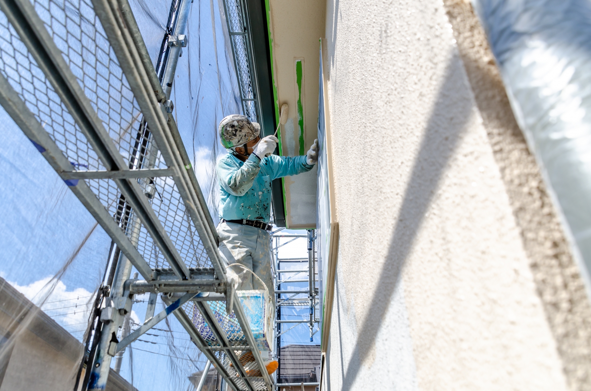 足場の上で高所作業を行う塗装職人